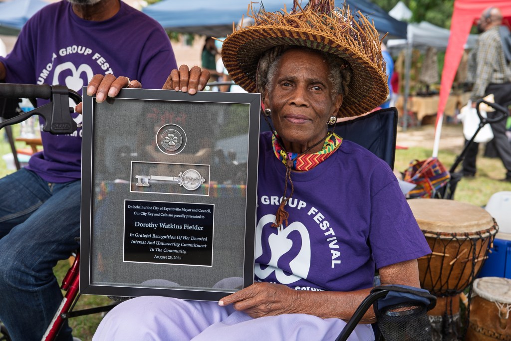 A woman holds a framed key to the city of Fayetteville