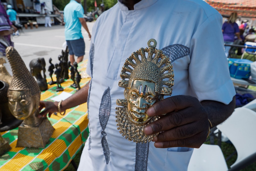 A Black man displays artwork at his festival booth