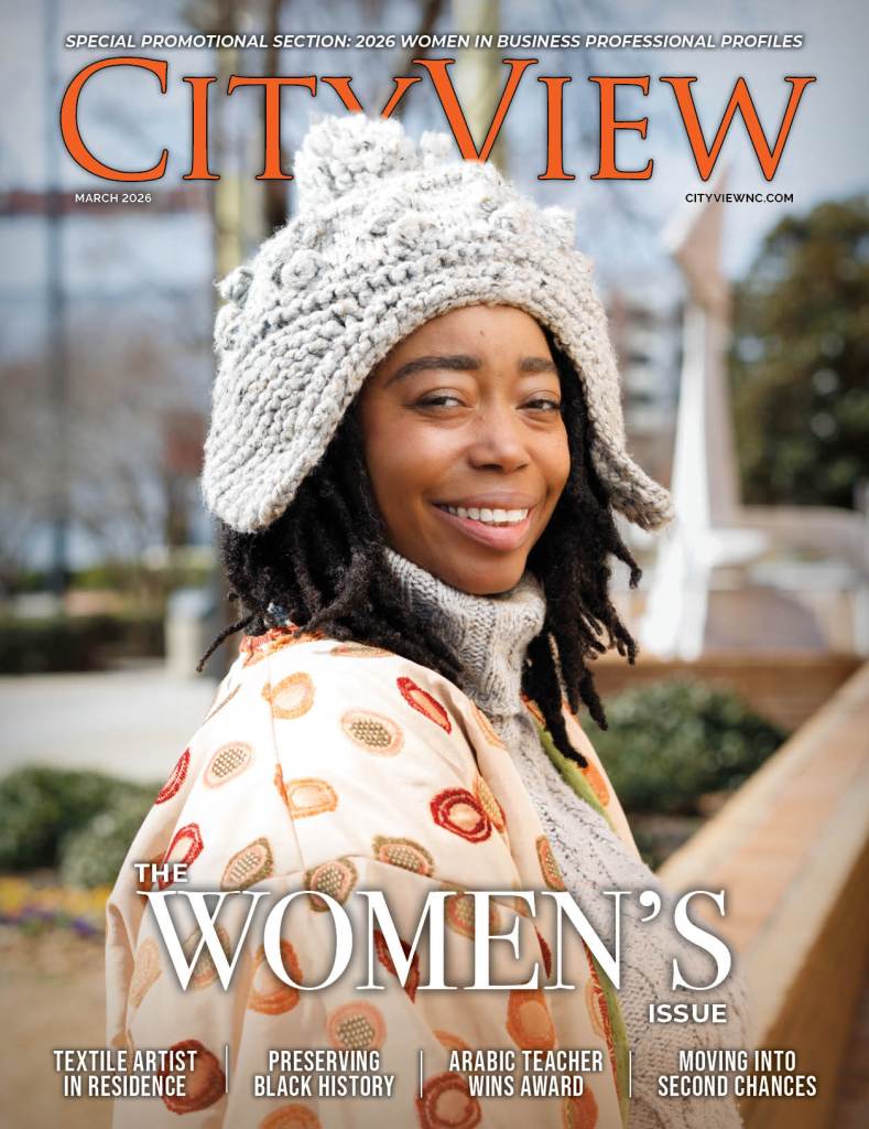 A woman smiles a the camera wearing clothing she made in her textile studio
