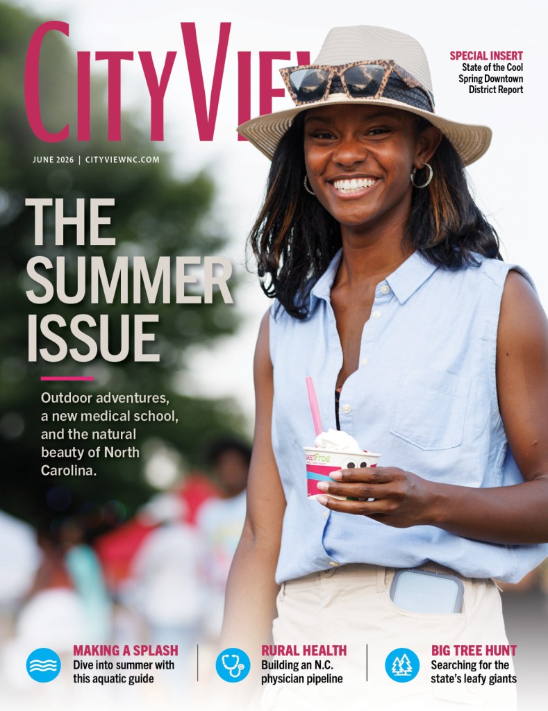 A Black woman wearing summer attire hods a sweetFrog cut with frozen yogurt and smiles at the camera.